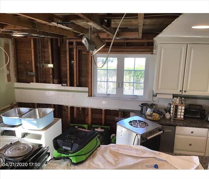 Kitchen with exposed framework and SERVPRO drying equipment 