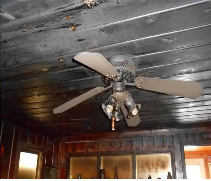 blackened and charred wood ceiling and wall panels, ceiling fan in place