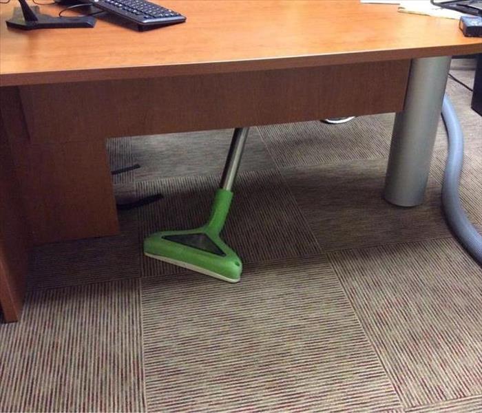 office with brown carpet and a wood desk, and a wand scrubbing the floor